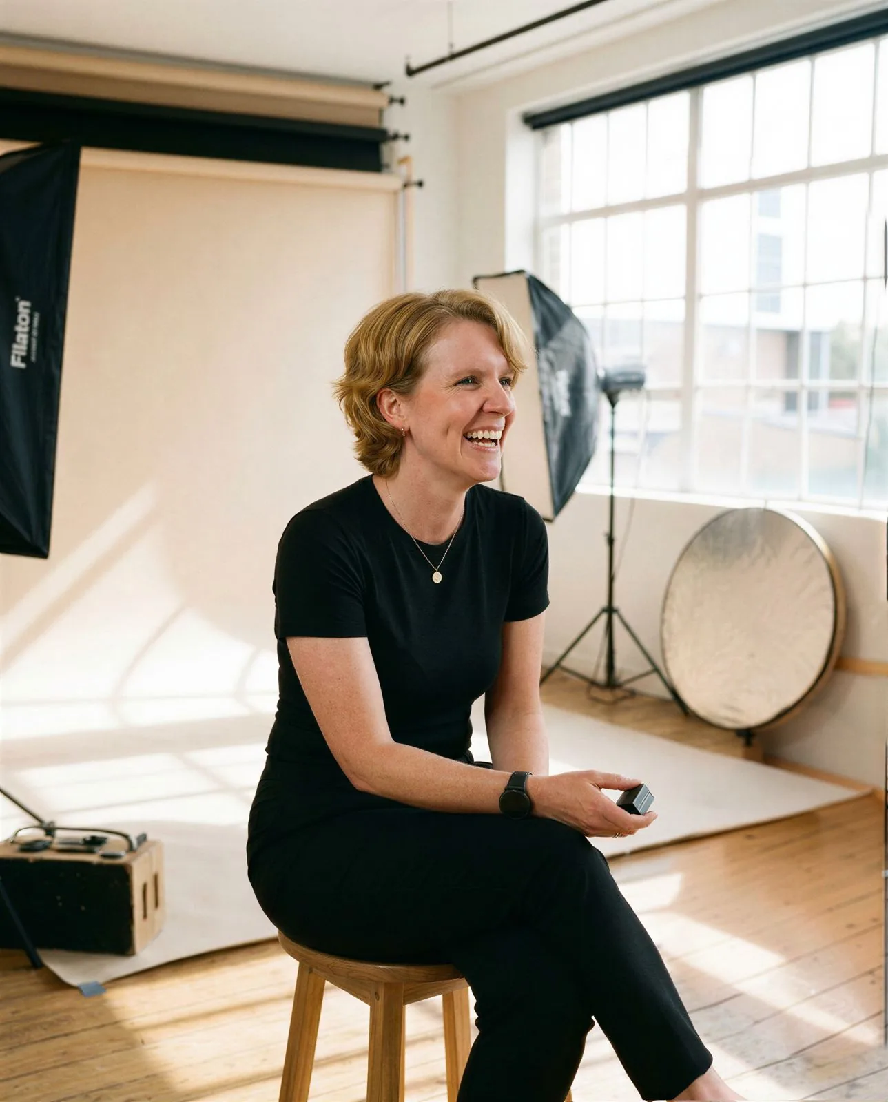 Seated studio portrait of an Allied Health Warrior mentor smiling in a bright photography studio with a neutral backdrop.